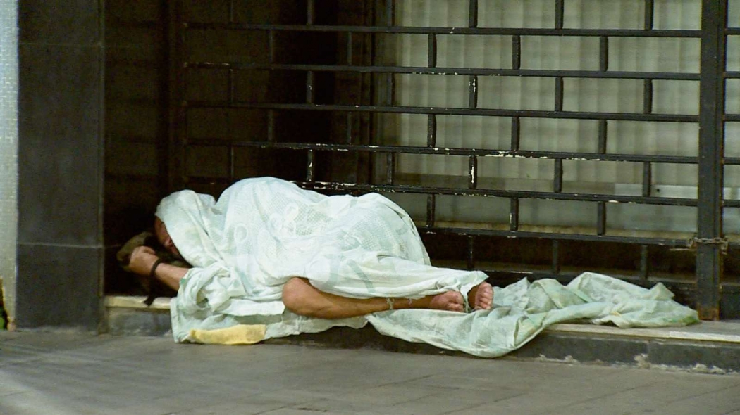 Homem improvisa com lençóis para se abrigar do frio embaixo de marquise. Crédito: Vinicius Gonçalves/TV Gazeta