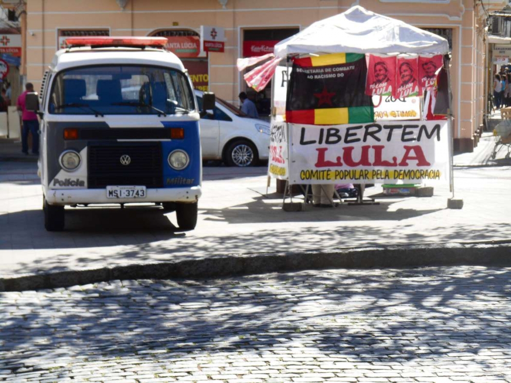 Na Praça Costa Pereira, uma cena inusitada. De um lado, a polícia, autoridade do Estado brasileiro. Do outro, um pedido por libertação de Lula, o presidiário. Crédito: Finesse Foto