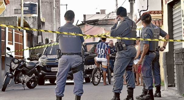 Polícia observa a perícia em cena de assassinato no bairro Divino Espírito Santo